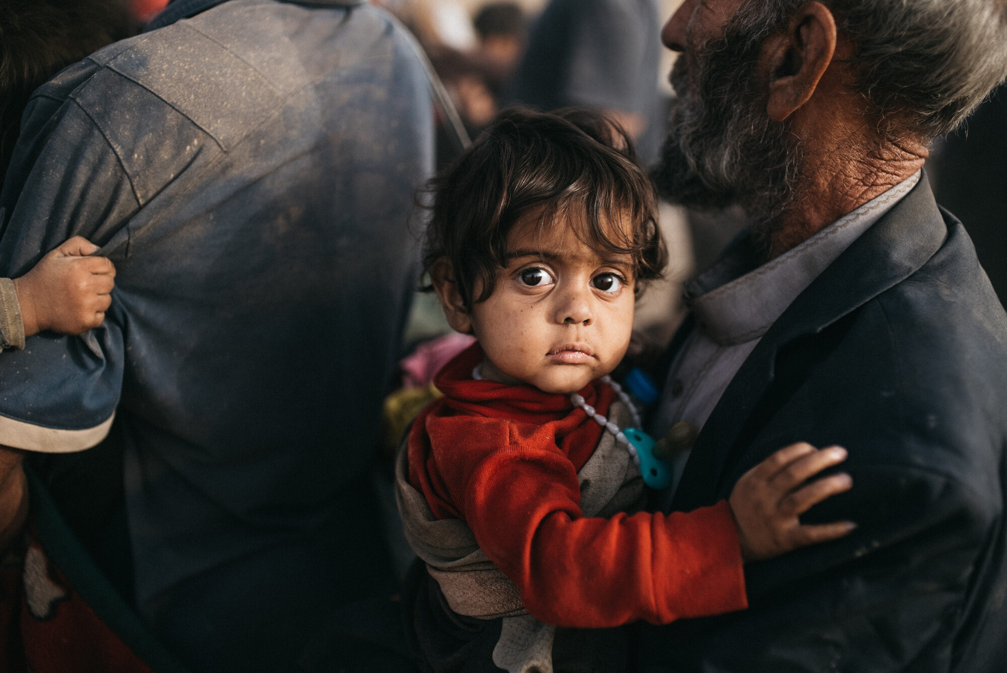 An elder holds a child in a displacement camp