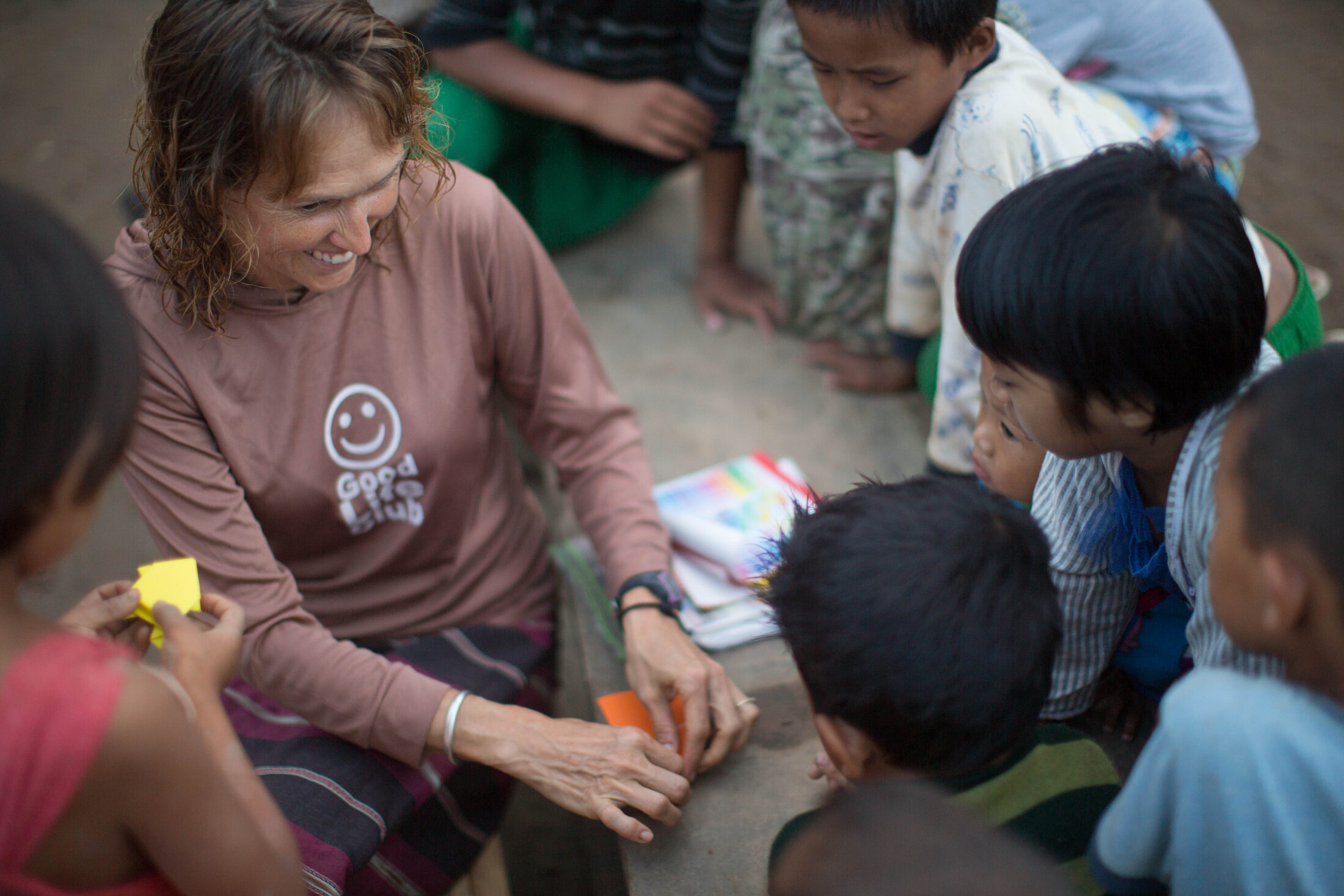 An aid worker makes origami with displaced children
